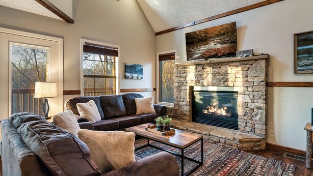 A cozy living room with a stone fireplace, leather sofas, and a coffee table.