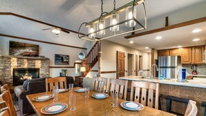 A spacious kitchen with a central island, wooden cabinetry, and a stone fireplace.