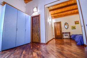Una habitación con piso de madera, un armario, una cama y un escritorio con una silla.