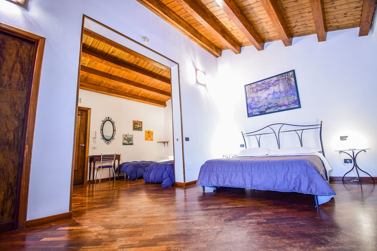 A bedroom with a wooden ceiling, a bed with a headboard, and a painting on the wall.