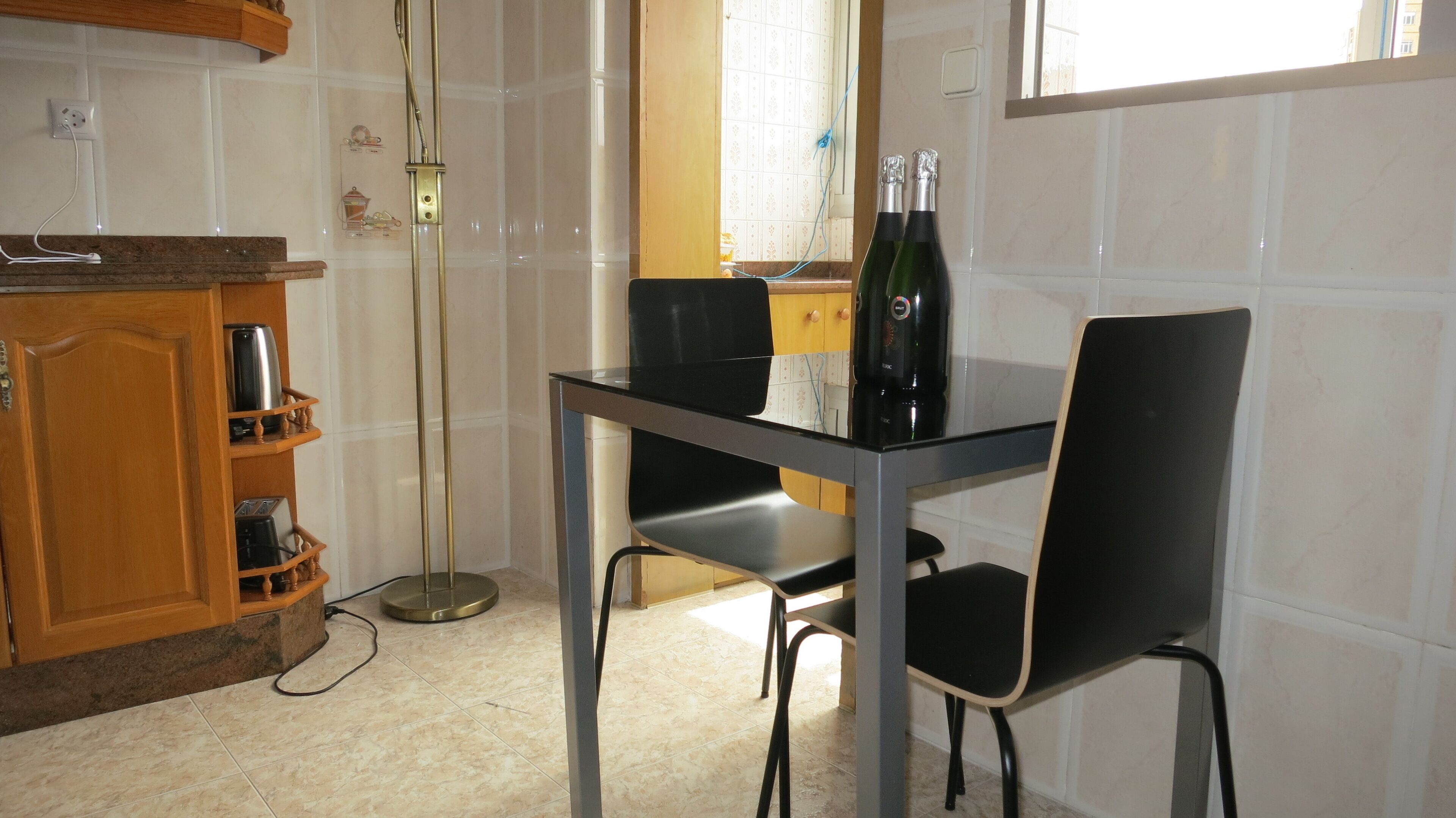Una cocina pequeña con una mesa de comedor, sillas, cafetera y un armario con electrodomésticos.