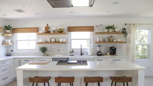 Una cocina moderna con una isla central, taburetes de bar y estanterías empotradas.