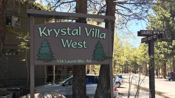 Schild für Krystal Villa West mit Berggrafik und der Adresse 134 Laurel Mt. Rd.