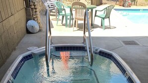Ein rechteckiger Swimmingpool mit einer Fliesenkante und einer Metallleiter.