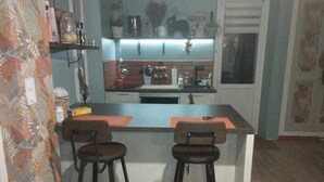 Una cucina compatta con un'isola centrale, due sgabelli da bar e un frigorifero.