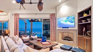 A spacious living room with a large sofa, a wooden coffee table, and a television mounted on the wall.