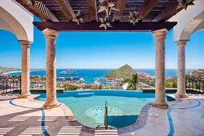 A pool area with clear blue water, surrounded by stone columns and a pergola with star-shaped decorations. - Private Designer Estate with Panoramic Views & Sophisticated Interiors (Cabo San Lucas)