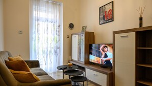 Un soggiorno con divano, televisione, mobile contenitore e finestra con tende.