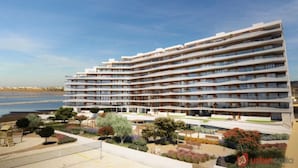 Een hotel met meerdere verdiepingen, balkons, een aangelegde tuin en uitzicht op het water.