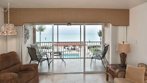 A living room with a view of a pool and ocean, furnished with a sofa, chairs, and a table. - Beautiful Bonita Beach Front Condo, Casa de Mimi in Dolphin Way (Bonita Springs)