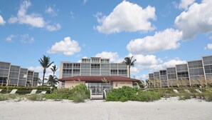 A hotel with a red-tiled roof, multiple floors, and a large glass facade. - Beautiful Bonita Beach Front Condo, Casa de Mimi in Dolphin Way (Bonita Springs)