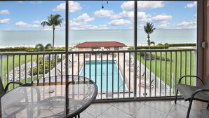 A balcony with a view of a swimming pool, palm trees, and the ocean. - Beautiful Bonita Beach Front Condo, Casa de Mimi in Dolphin Way (Bonita Springs)