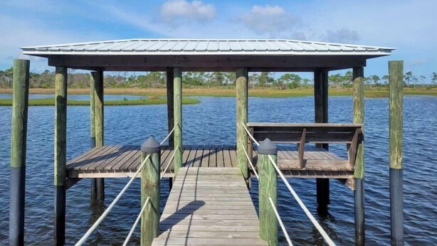 A wooden pier leading to a covered gazebo over water. - Waterfront RV Site with Dock (Port St. Joe)