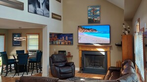 A spacious living room with a fireplace, leather sofas, a flat-screen TV, and artwork on the walls.