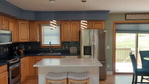 Une cuisine moderne avec des meubles en bois, un réfrigérateur en acier inoxydable et un îlot central doté de tabourets.