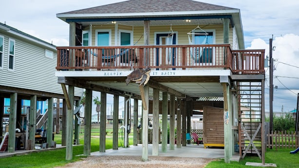 Une maison à deux étages avec un balcon et une terrasse en bois.