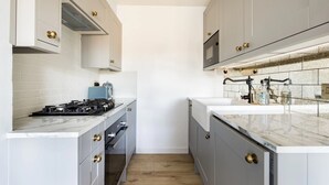 Una cocina moderna con armarios grises, encimera blanca y horno empotrado.
