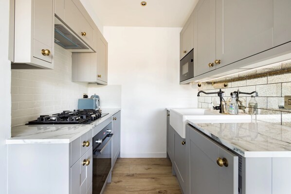 Una cocina moderna con armarios grises, encimera blanca y horno empotrado.