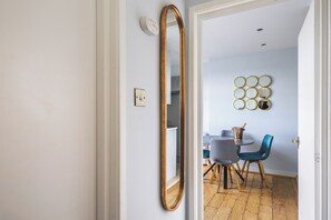 Une pièce dotée d’un grand miroir, d’un coin repas avec une table et des chaises, et d’un miroir rond fixé au mur, servant d’élément décoratif.