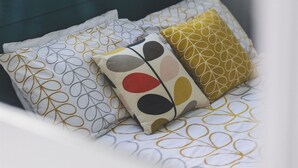 Una cama con cabecera color turquesa y ropa de cama estampada.