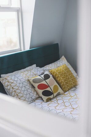 Una cama con cabecera color turquesa y ropa de cama estampada.
