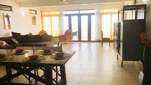 A spacious living area with a dining table set for four, a sofa, and a chair.