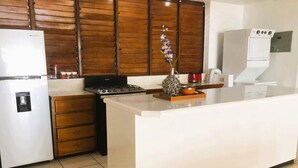 A kitchen with a central island, wooden cabinets, a refrigerator, a stove, and a sink.