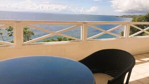 A balcony with a view of the sea, a table, and a chair.