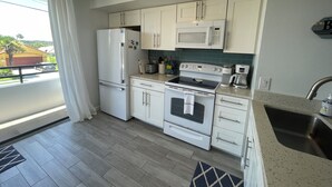 Una cocina moderna con armarios blancos, horno empotrado, microondas y refrigerador.