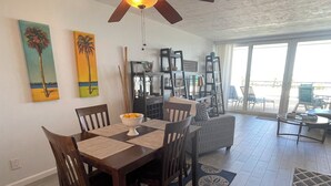 Un comedor con mesa y sillas de madera, ventilador de techo y obras de arte en las paredes.