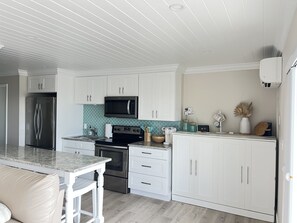 A modern kitchen with white cabinetry, a stainless steel refrigerator, a microwave, and a stove. - Beautiful Ocean Access Islamorada Condo. MM 76.5 Bring your Boat (Islamorada)