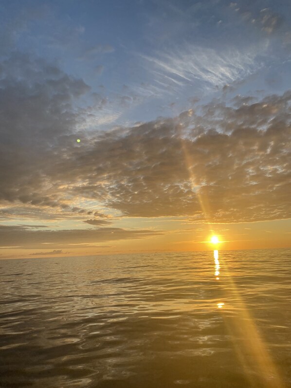 A sunset over a calm sea with a clear sky.