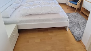 A bedroom with a bed, a bookshelf, a wicker chair, a view of the sea, and a balcony. - Herring Gull - Fantastic sea view (Cuxhaven)