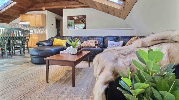 Un salon chaleureux avec un canapé en cuir, une table basse en bois et une grande plante.