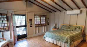 Une chambre à coucher avec un lit, une table de chevet, une chaise et une fenêtre donnant sur un beau paysage.