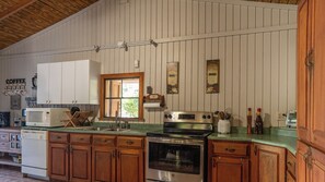 Une cuisine avec des armoires en bois, un four en acier inoxydable, un four à micro-ondes et une fenêtre.