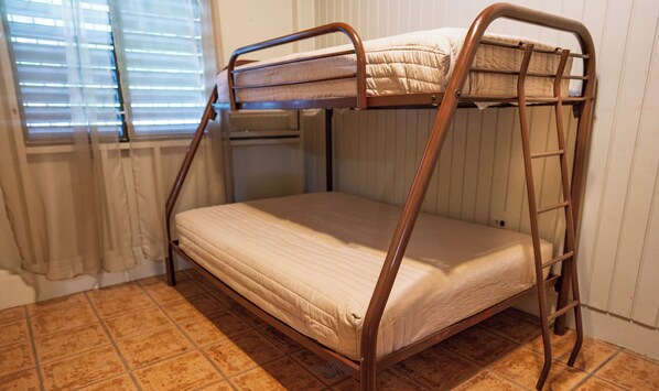 A bunk bed with a ladder, a window with blinds, and a tiled floor.