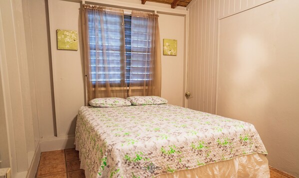 Un dormitorio con cama, cortinas y dos luces fijadas a la pared.