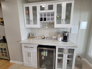 Kitchen area with refrigerator, white cabinetry, and coffee maker.