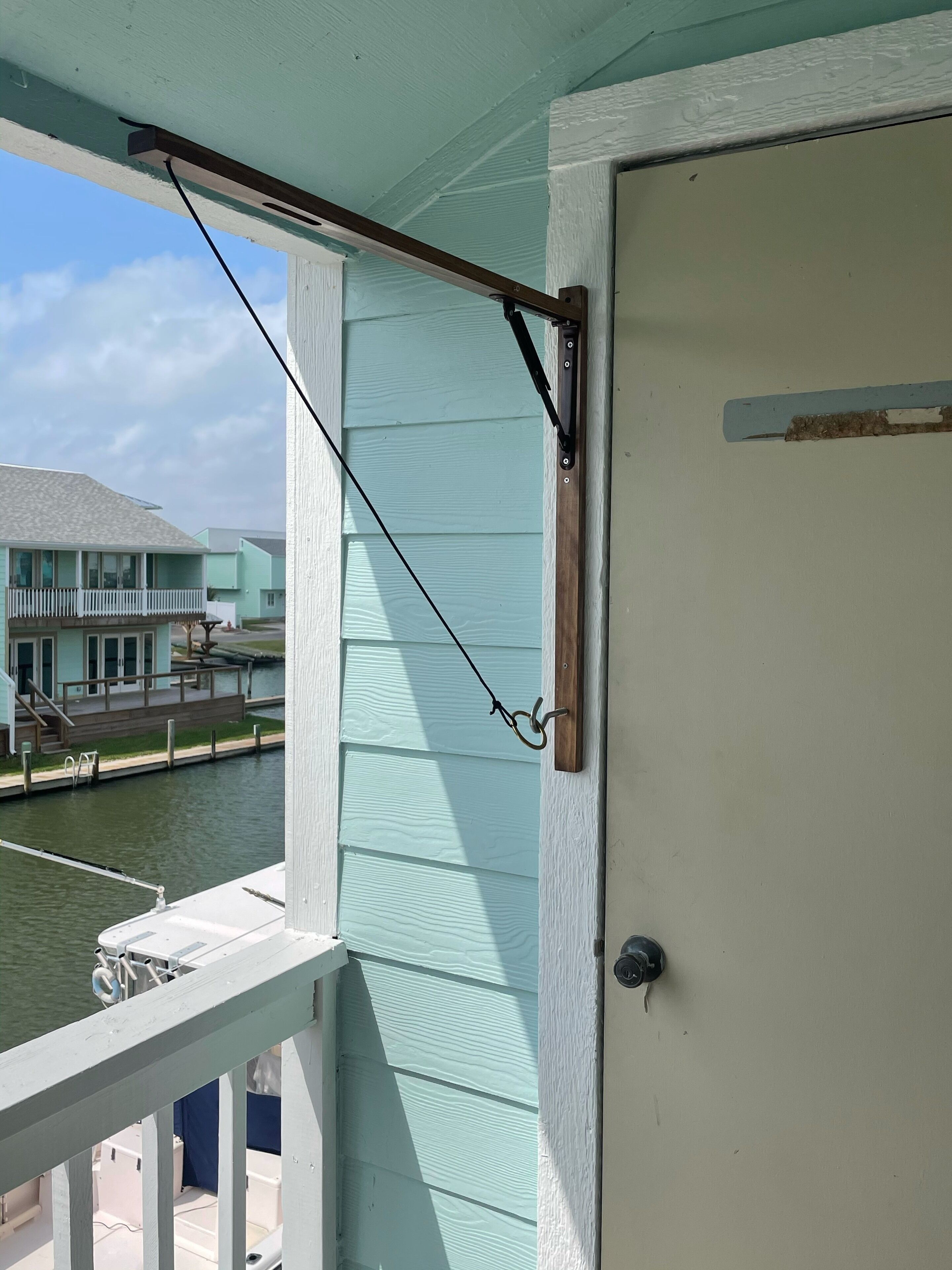 A balcony with a metal railing, a door, and a view of a water body and buildings in the background.