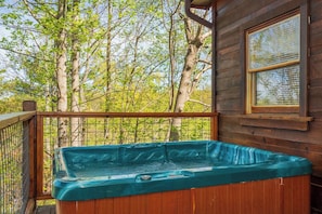 A hot tub on a wooden deck with a view of trees.