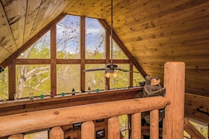 A wooden interior with a sloped ceiling, a wooden railing, and a bear decoration.