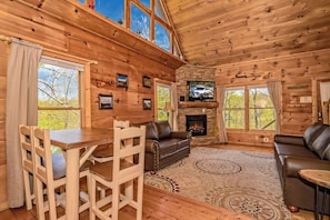 A log cabin interior with a fireplace, seating area, and a television.