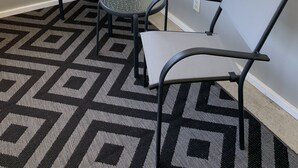 A corner room with two chairs, a small table, a patterned rug, and a window with blinds. - Perfect Location Just 0.5 Miles from Notre Dame’s Campus! (South Bend)