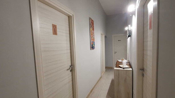 A hallway with closed doors, a small table with items, and a light fixture. - Apartment within walking distance of the Archaeological Excavations (Ercolano)