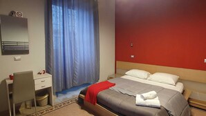 A hotel room with a bed, a desk, a chair, a mirror, and a window with curtains. - Apartment within walking distance of the Archaeological Excavations (Ercolano)
