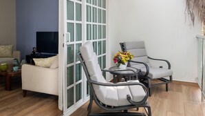 Un salon avec un canapé, deux fauteuils, une petite table et un téléviseur.
