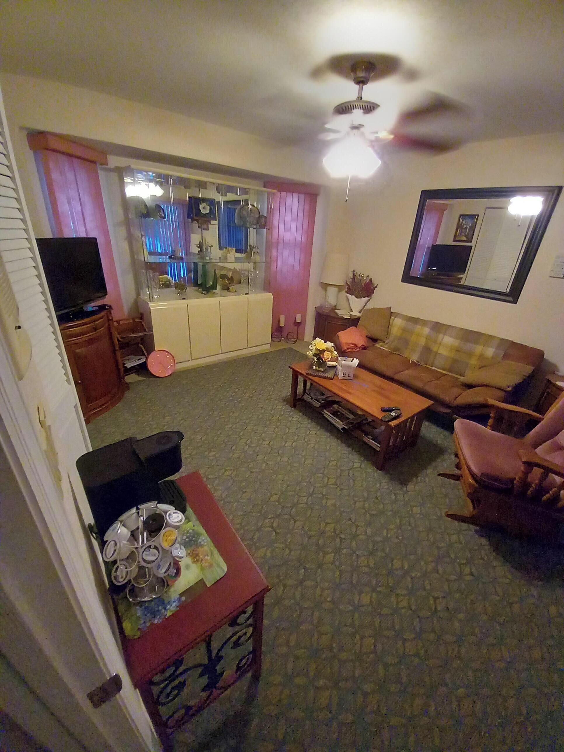 Un salon équipé d’un téléviseur, d’un canapé, d’une table basse et d’un ventilateur de plafond.