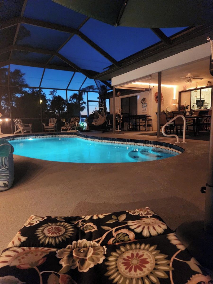 An indoor swimming pool with a covered area, lounge chairs, and a bar area.