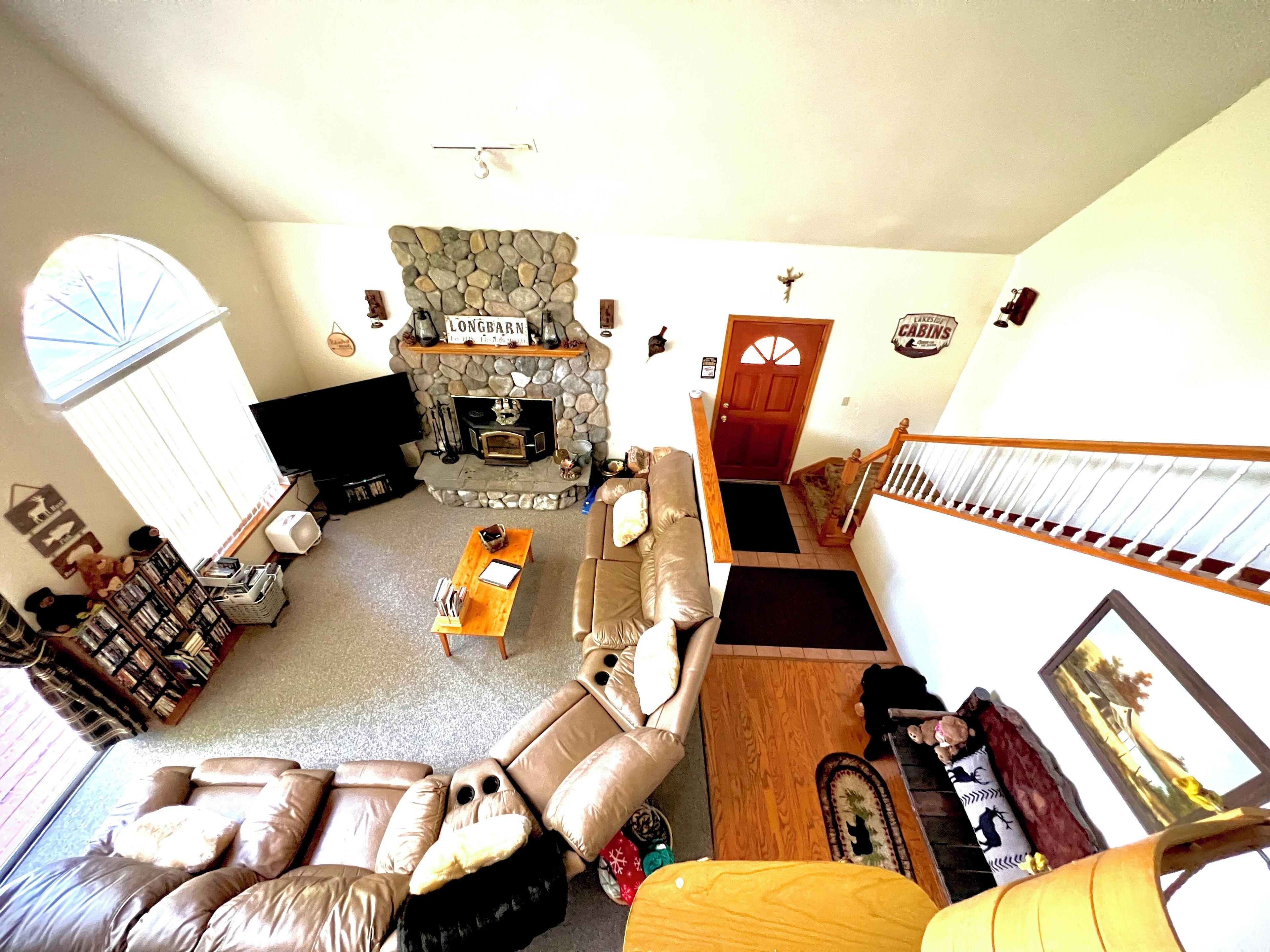 A spacious living room with a stone fireplace, a comfortable sofa, and a television.